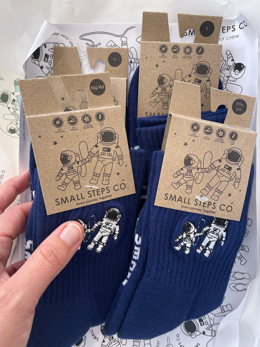 Small Steps Co. sock packaging with recycled kraft tags in adult and kids sizes