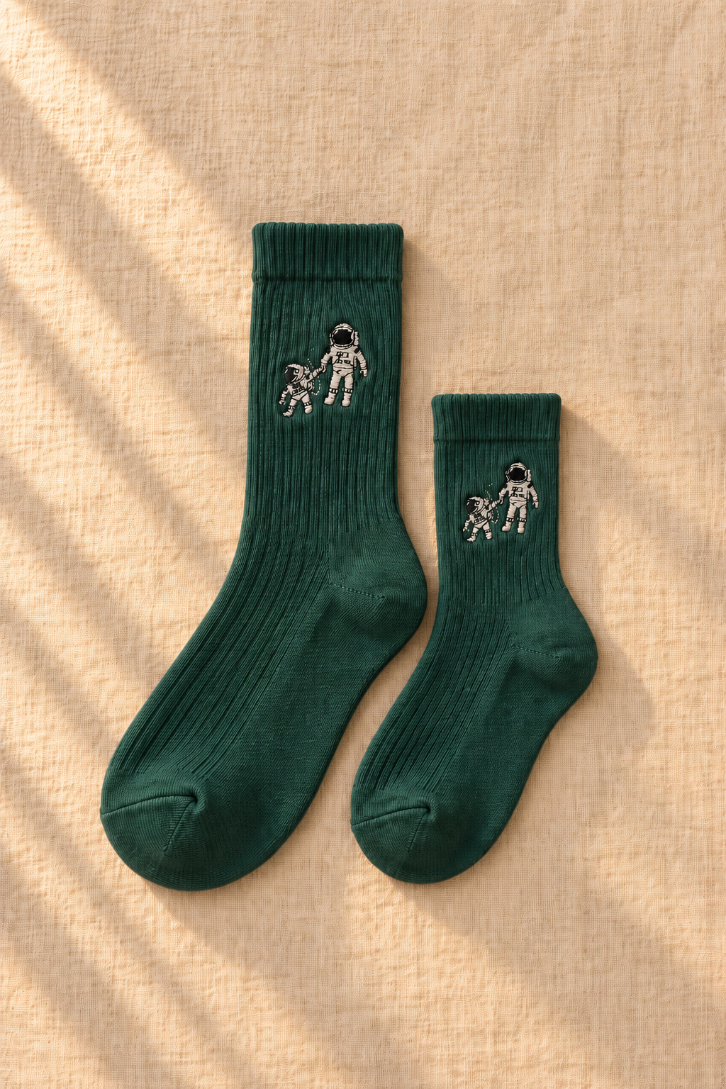 Small Steps Co. matching deep green bamboo socks for adult and child, on linen