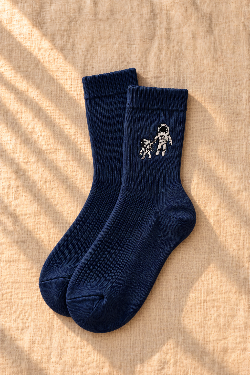 Small Steps Co. women's navy bamboo crew socks with astronaut emblem, on linen