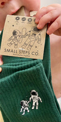 Child holding Small Steps Co. deep green bamboo socks with kraft tag
